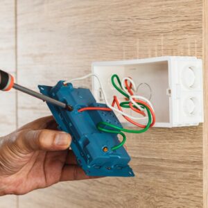 hand-of-an-electrician-is-using-a-screwdriver-to-attach-the-wires-to-the-socket-with-a-plastic-box-on_t20_mlV713